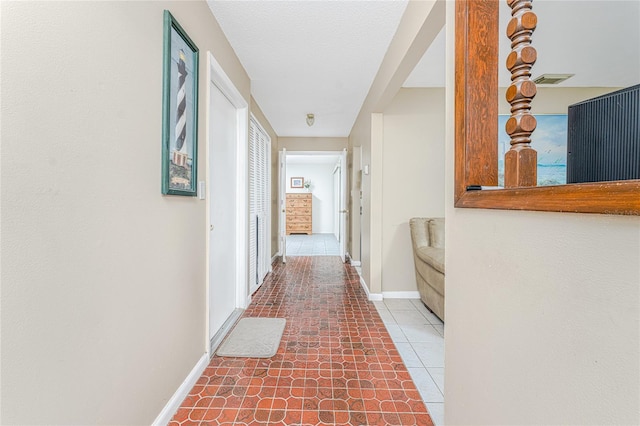 hallway with a textured ceiling and tile patterned floors