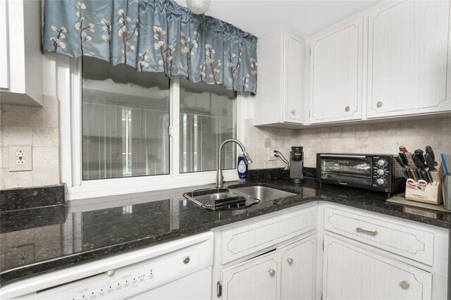 kitchen featuring decorative backsplash, white cabinets, white dishwasher, sink, and dark stone countertops