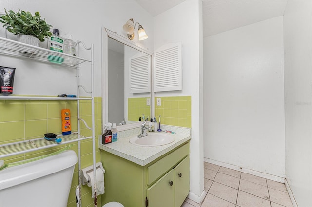 bathroom featuring toilet, tile patterned flooring, tasteful backsplash, vanity, and tile walls