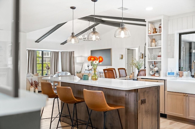 kitchen featuring pendant lighting, sink, lofted ceiling with beams, and light wood-type flooring