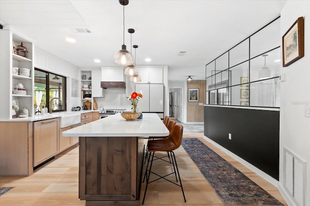 kitchen featuring sink, dishwashing machine, white refrigerator, a center island, and light hardwood / wood-style flooring