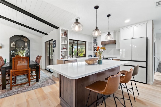 kitchen featuring vaulted ceiling with beams, white cabinets, white fridge, a center island, and light hardwood / wood-style floors