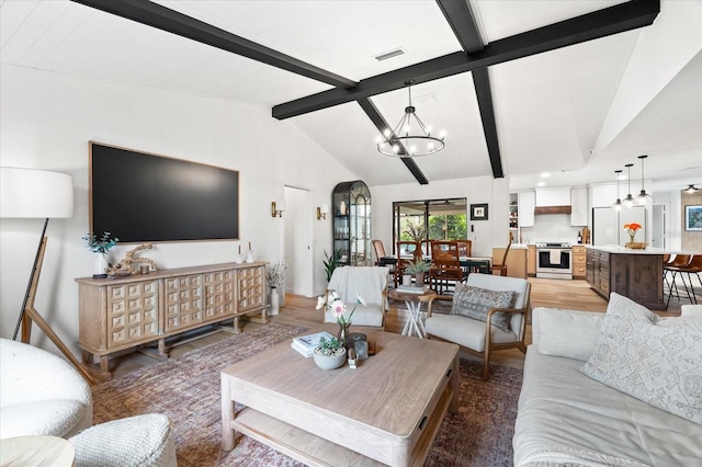 living room featuring hardwood / wood-style floors, lofted ceiling with beams, and a chandelier