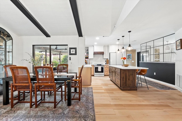 dining area with beam ceiling and light hardwood / wood-style flooring