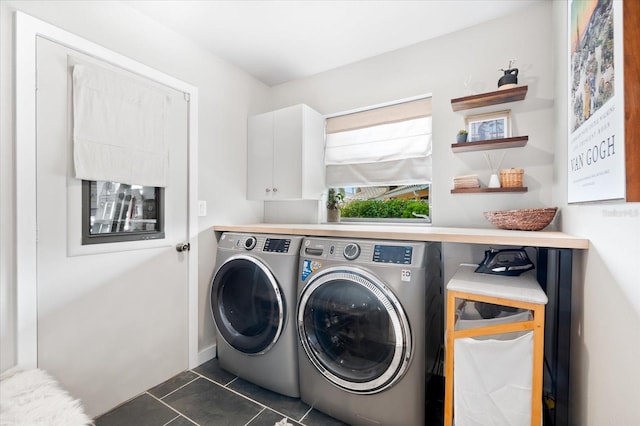 laundry area featuring cabinets, dark tile patterned flooring, and washer and dryer