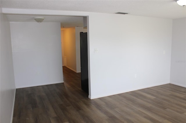 empty room with a textured ceiling and wood-type flooring