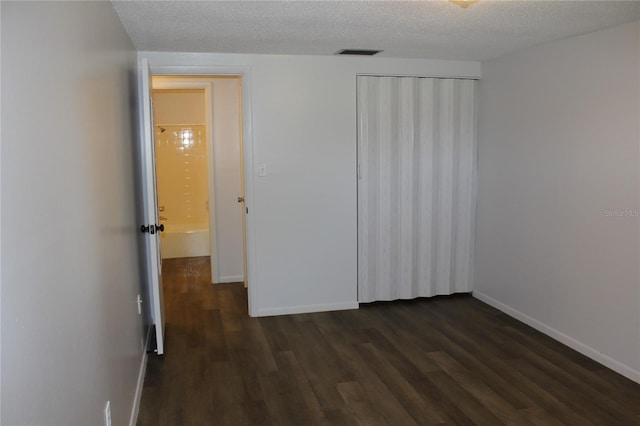 unfurnished bedroom with dark hardwood / wood-style floors and a textured ceiling