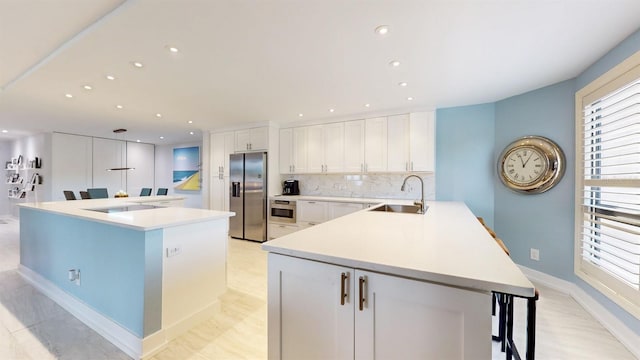 kitchen featuring a sink, light countertops, stainless steel fridge, and white cabinetry