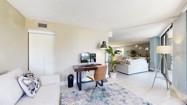 office area with light wood-style floors, visible vents, and baseboards