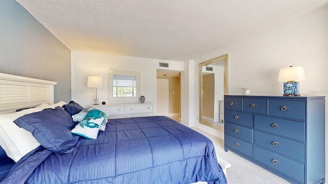 bedroom with light carpet, visible vents, and a textured ceiling