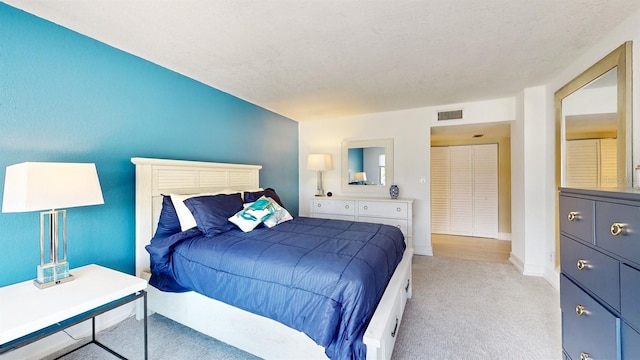 bedroom with light carpet, a textured ceiling, visible vents, and baseboards