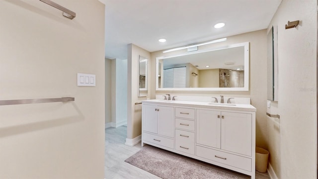 bathroom featuring recessed lighting, a sink, baseboards, and double vanity