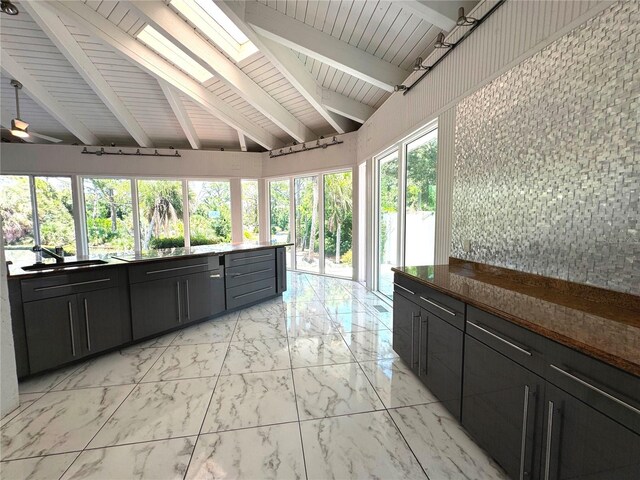 interior space with ceiling fan, sink, vaulted ceiling with skylight, and wood ceiling