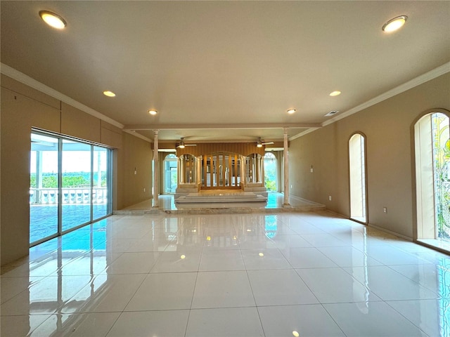 empty room with ceiling fan, plenty of natural light, ornamental molding, and light tile patterned floors