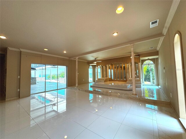 spare room featuring ceiling fan, ornamental molding, and light tile patterned floors