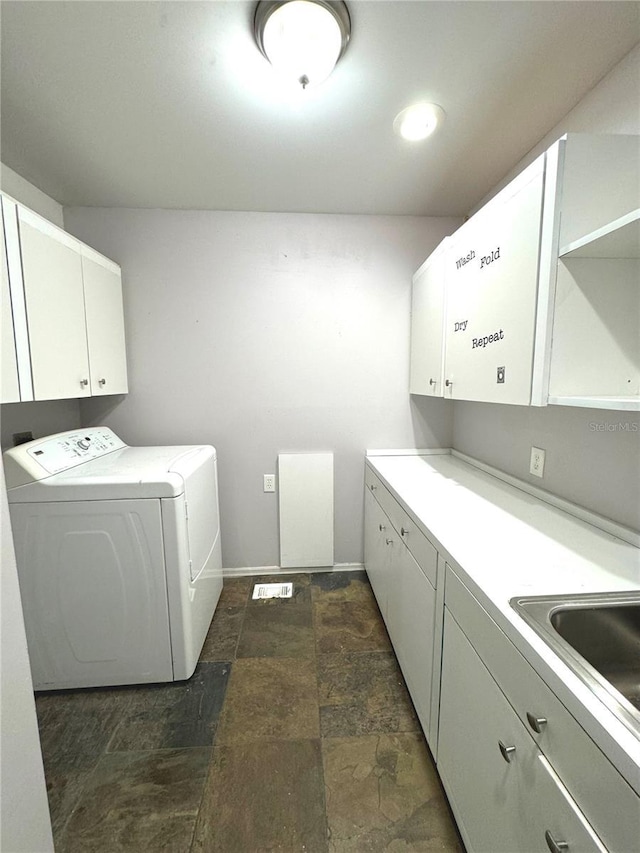 clothes washing area with dark tile patterned flooring, cabinets, and washer and clothes dryer