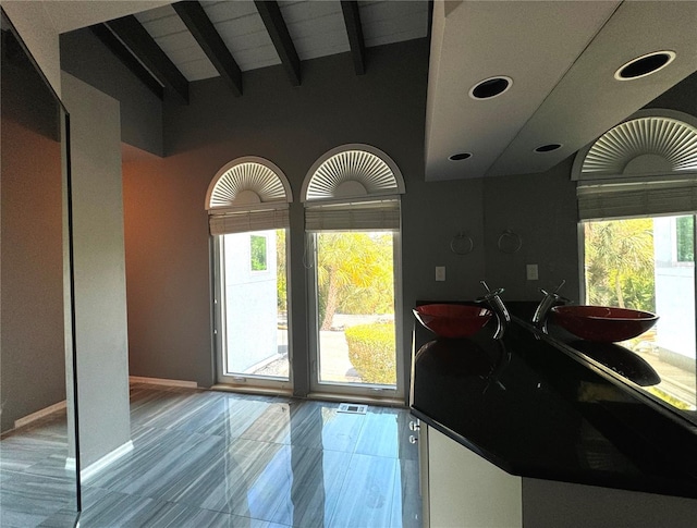 interior space with tile patterned flooring and vaulted ceiling with beams