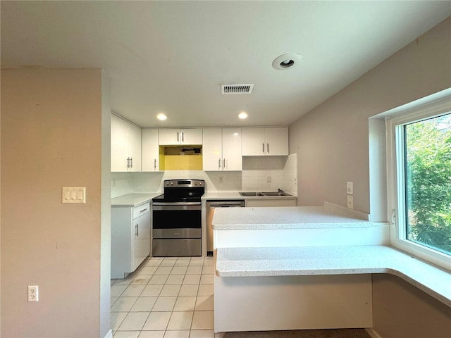 kitchen with kitchen peninsula, white cabinets, light tile patterned floors, stainless steel appliances, and sink