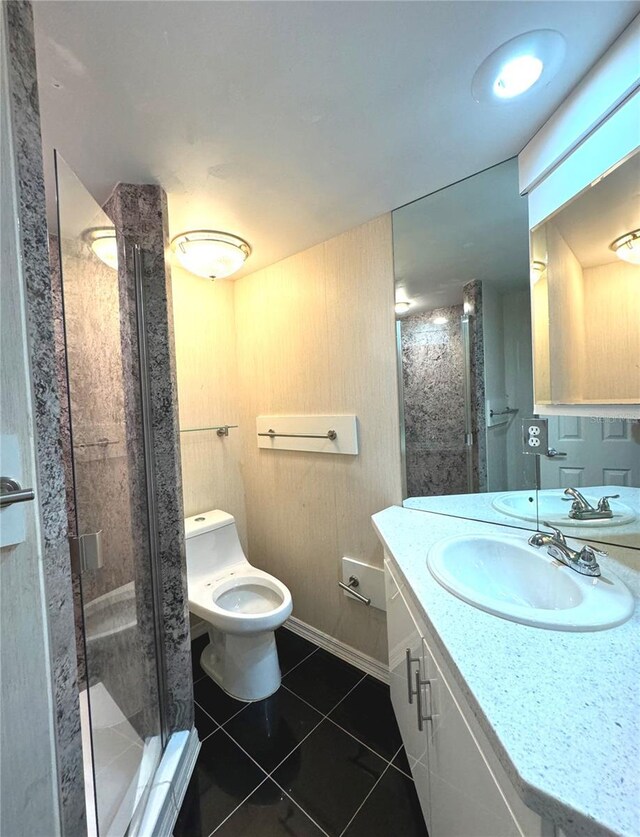 bathroom with a shower with door, toilet, vanity, and tile patterned flooring