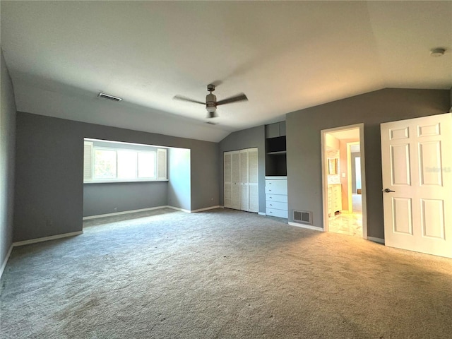 unfurnished bedroom featuring lofted ceiling, connected bathroom, ceiling fan, and carpet floors