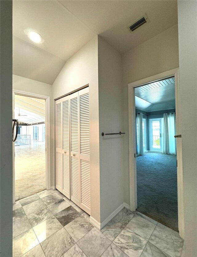 hall featuring vaulted ceiling and light colored carpet