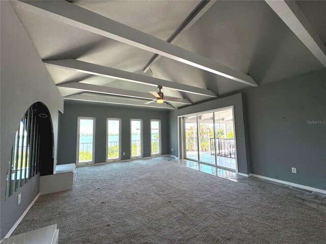 unfurnished living room featuring ceiling fan, carpet floors, and vaulted ceiling with beams