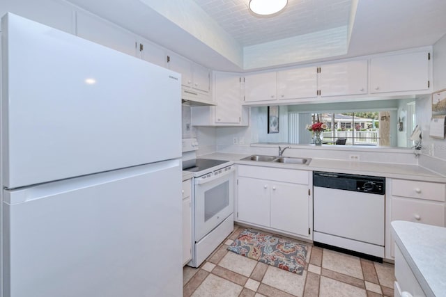 kitchen featuring white appliances, white cabinets, light tile patterned flooring, sink, and a tray ceiling