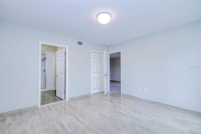 unfurnished bedroom featuring ensuite bath and light hardwood / wood-style flooring