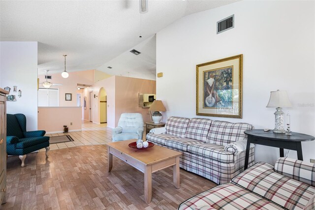 living room featuring ceiling fan, vaulted ceiling, a textured ceiling, and hardwood / wood-style flooring