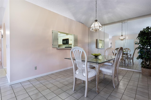 tiled dining space with a notable chandelier, a textured ceiling, and vaulted ceiling