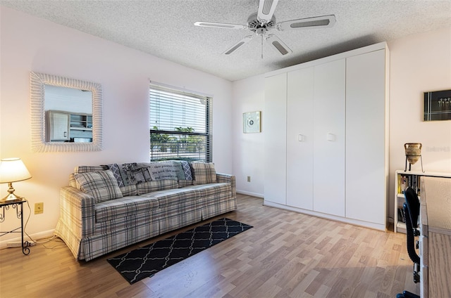 living room featuring ceiling fan, a textured ceiling, and hardwood / wood-style floors