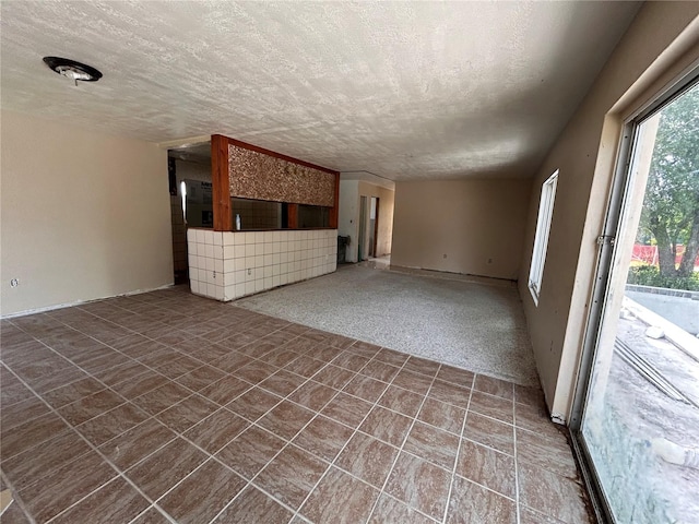 unfurnished living room featuring dark tile patterned floors, a textured ceiling, and a healthy amount of sunlight