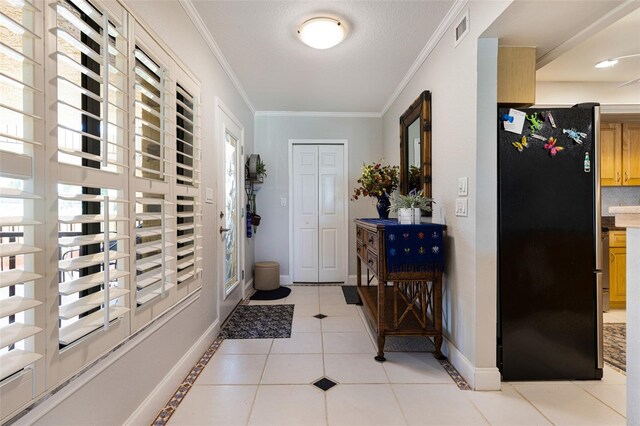 tiled entrance foyer featuring ornamental molding and a wealth of natural light