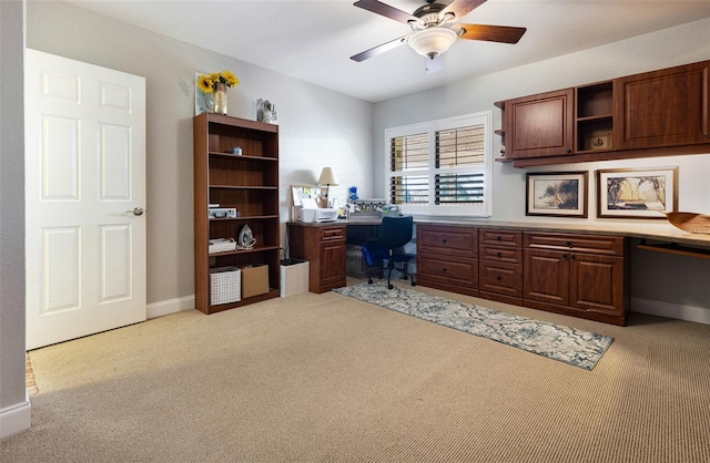 office area featuring light carpet, built in desk, and ceiling fan