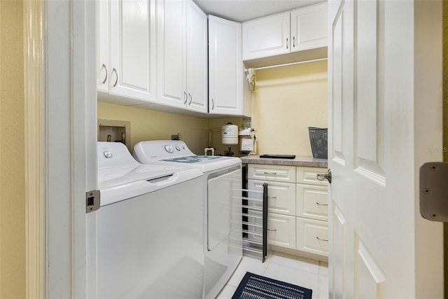 laundry room with cabinets, washing machine and dryer, and light tile patterned floors