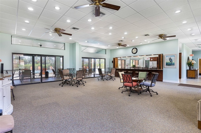 interior space with a drop ceiling, ceiling fan, and a high ceiling