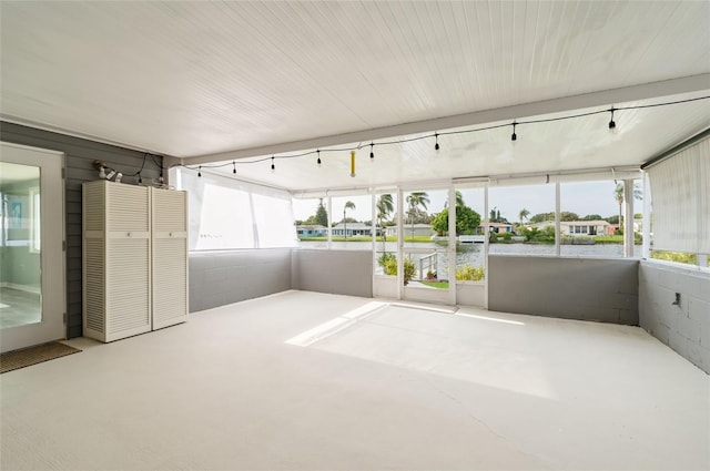 unfurnished sunroom with a water view, track lighting, and plenty of natural light