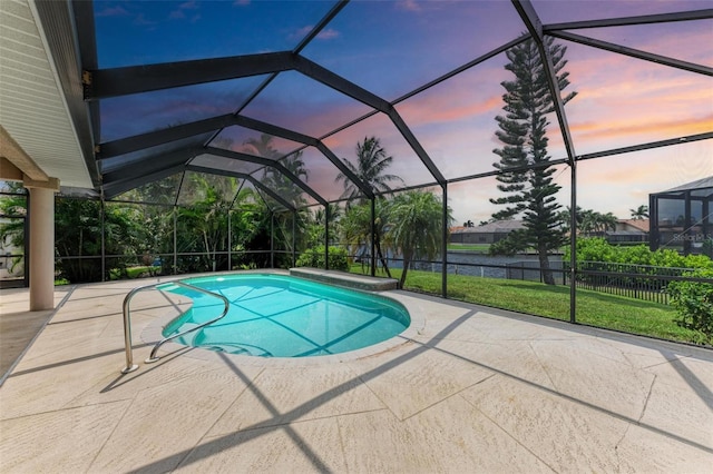 pool at dusk featuring glass enclosure and a patio