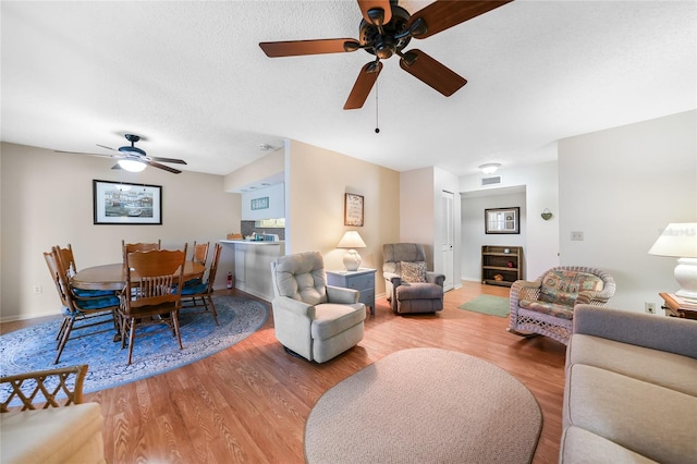 living room featuring ceiling fan, hardwood / wood-style flooring, and a textured ceiling