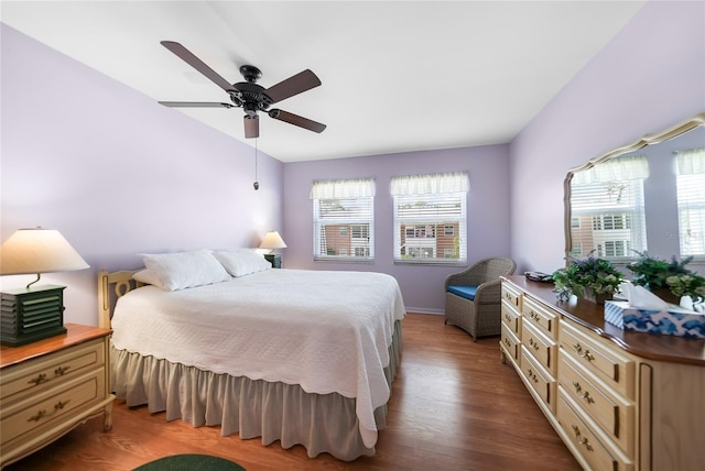 bedroom with lofted ceiling, multiple windows, a ceiling fan, and wood finished floors