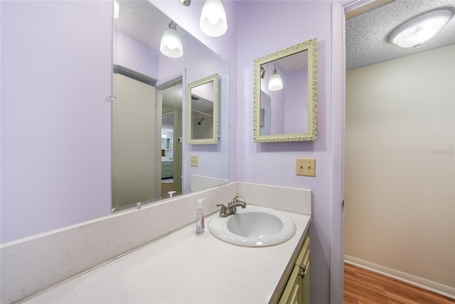 bathroom with a textured ceiling, vanity, and hardwood / wood-style floors