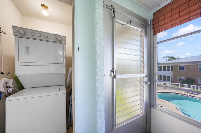 clothes washing area featuring stacked washer and clothes dryer and a healthy amount of sunlight