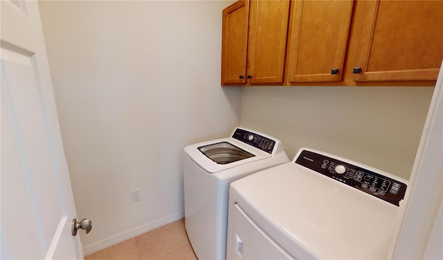 washroom featuring washer and clothes dryer, light tile patterned floors, and cabinets