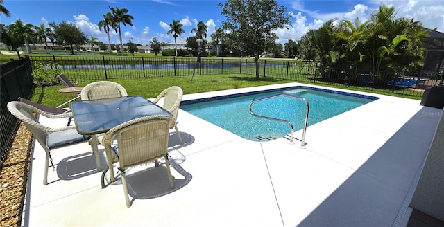 view of pool with a lawn, a water view, and a patio