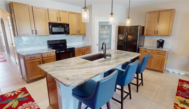 kitchen featuring a kitchen breakfast bar, a kitchen island with sink, sink, black appliances, and pendant lighting