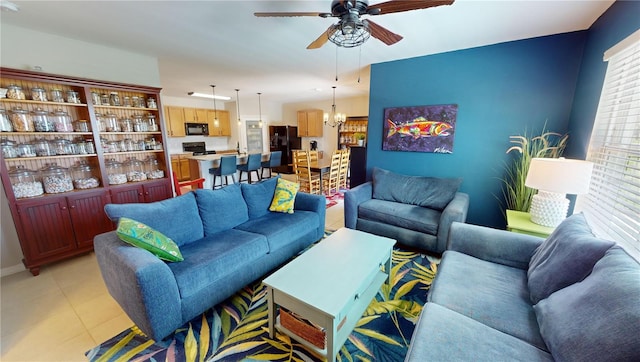 tiled living room with ceiling fan with notable chandelier