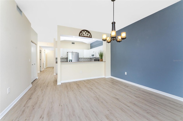 unfurnished living room with light hardwood / wood-style floors and a chandelier