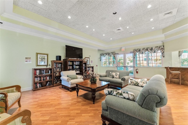 living room featuring light hardwood / wood-style flooring, a raised ceiling, and ornamental molding