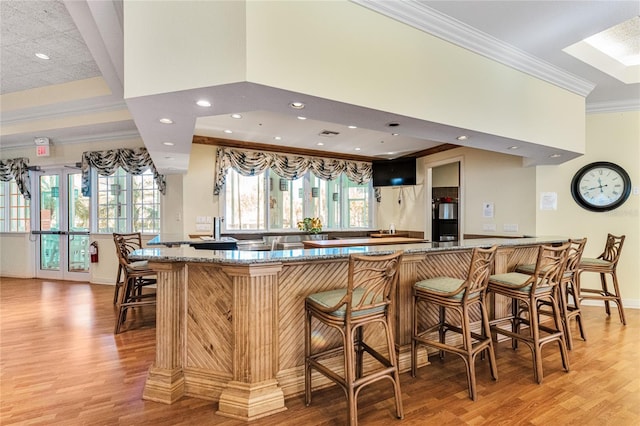 interior space featuring a skylight, stone countertops, light hardwood / wood-style flooring, and ornamental molding