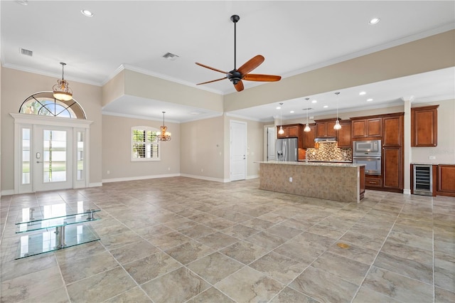 unfurnished living room featuring ornamental molding, wine cooler, visible vents, and baseboards